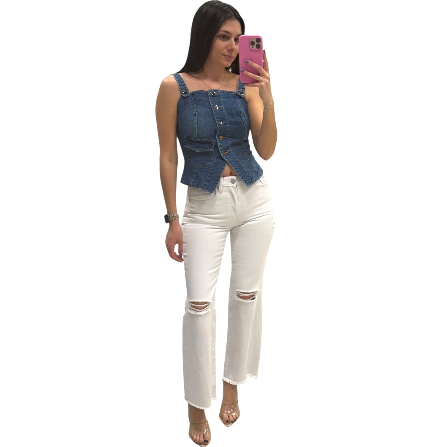 Woman wearing a denim top and white pants taking a mirror selfie.