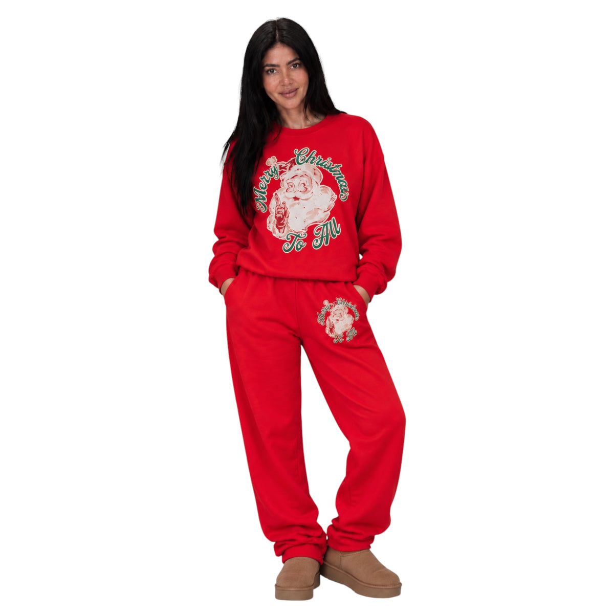 A woman modeling a red Christmas-themed sweatshirt and jogger pants set. The sweatshirt features a large graphic of Santa Claus with 'Merry Christmas' written in green and white.