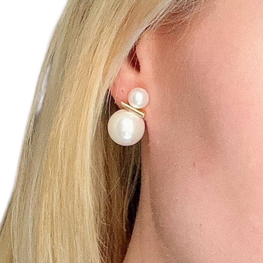 Pearl earring worn by a person with blonde hair on a white background