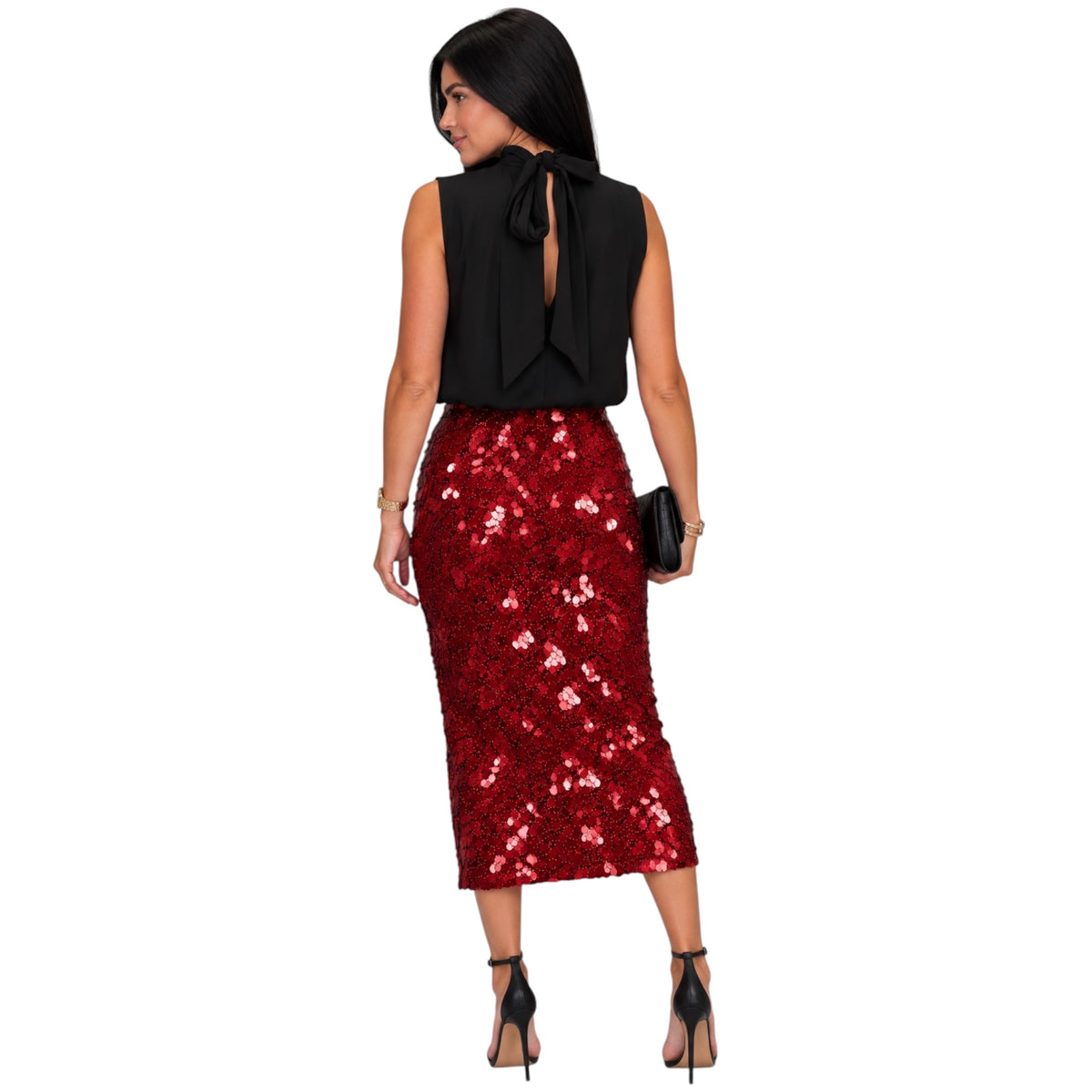 A woman shown from the back wearing a sleeveless black top with a large bow at the open back and a red sequined midi skirt, paired with black high heels and holding a small black clutch against a plain white background.