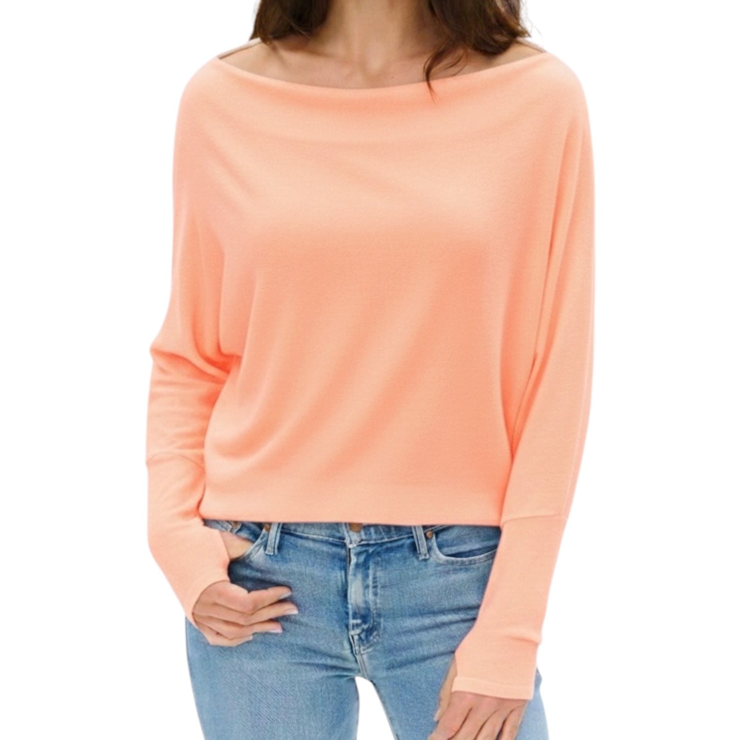 Person wearing a peach long-sleeve top and blue jeans on a white background