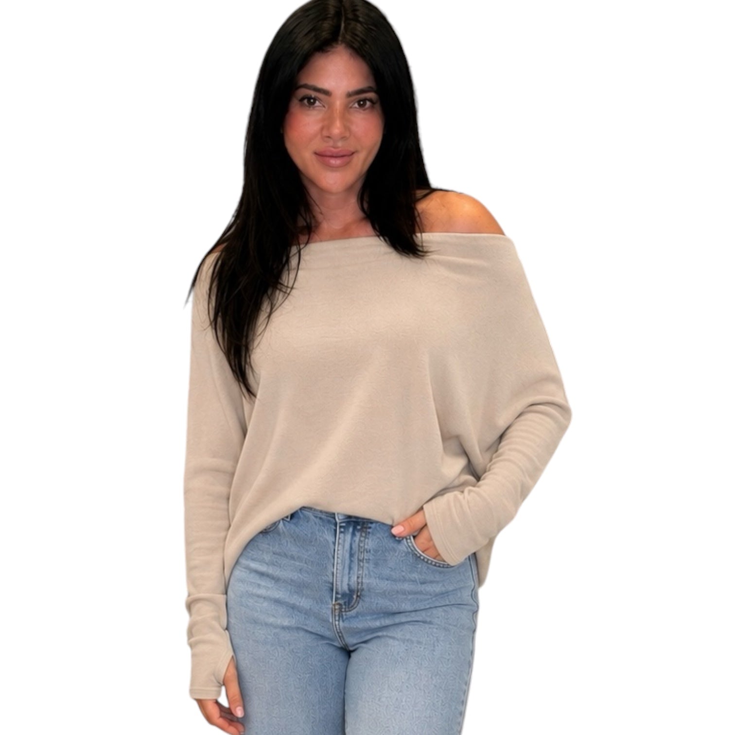 Woman wearing a beige off-shoulder sweater and blue jeans on a white background