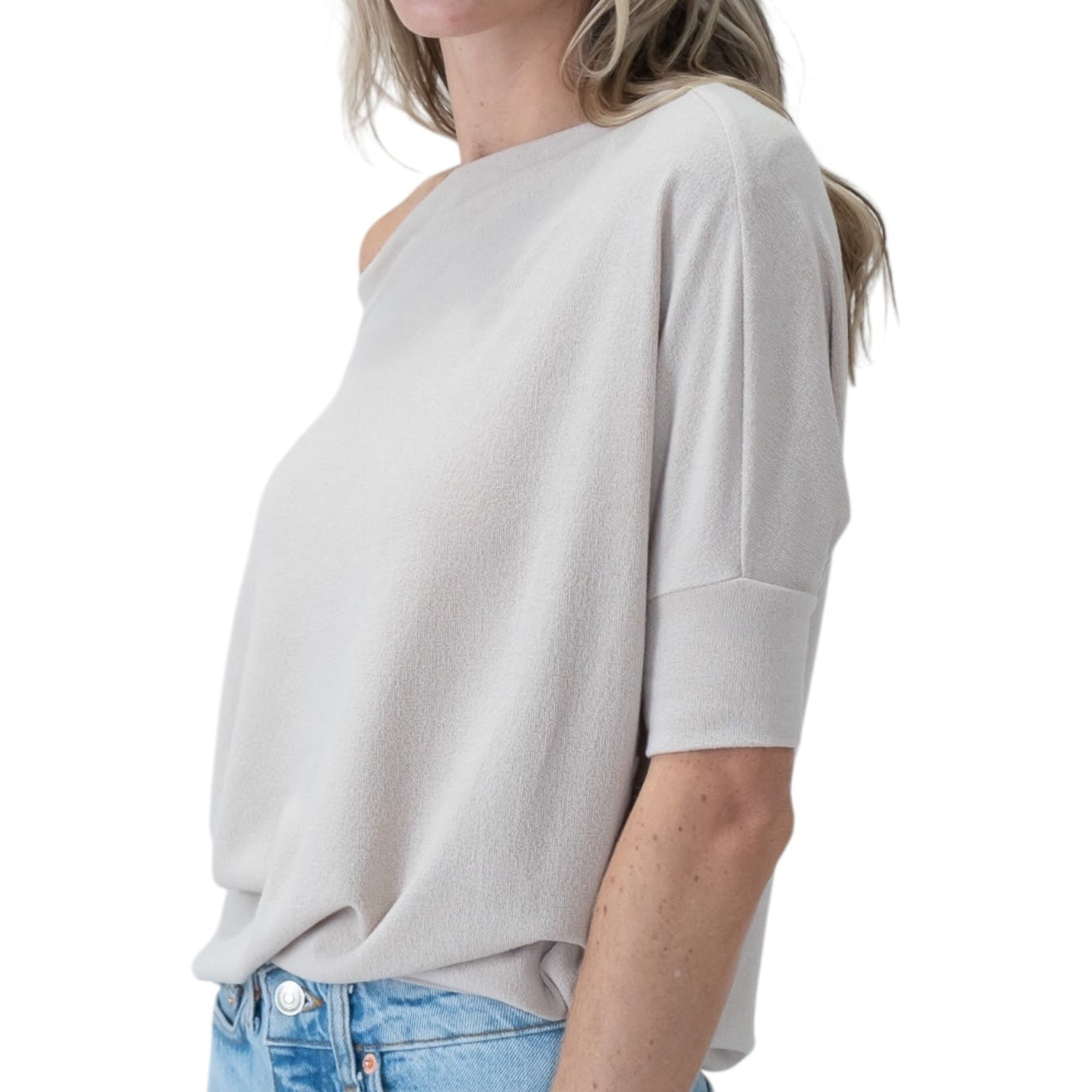 Woman wearing a taupe oversized shirt and blue jeans on a white background
