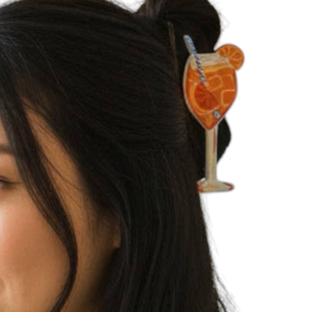 Hair clip shaped like a cocktail with an orange slice and straw on a white background