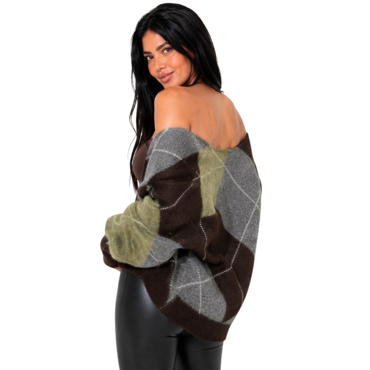 A woman modeling an off-the-shoulder knit sweater with an argyle pattern in brown, gray, and olive green, paired with black pants against a plain white background.