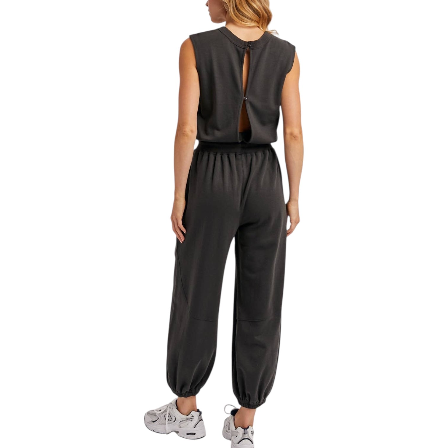 Person wearing a dark grey sleeveless jumpsuit on a white background