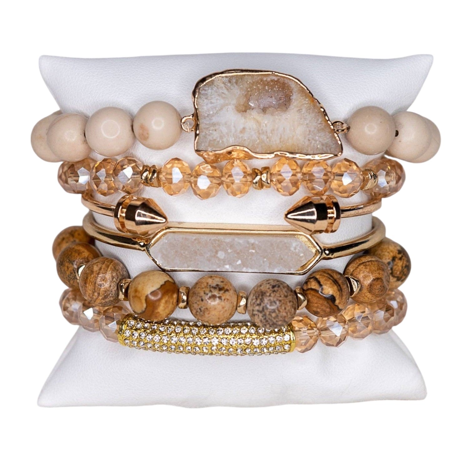 Stack of beaded and gold bracelets on a white stone surface