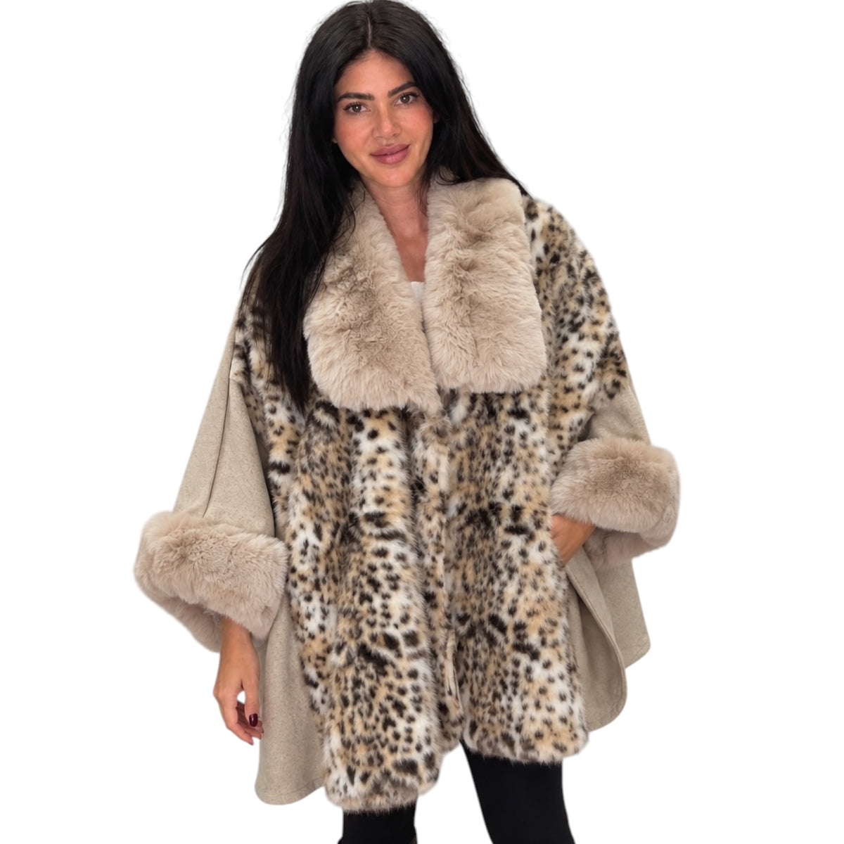 A woman modeling a leopard-print faux fur poncho with beige faux fur trim on the collar and cuffs, set against a plain white background.