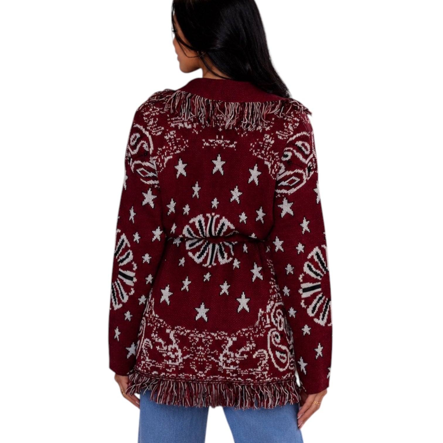 A woman shown from the back wearing a burgundy cardigan sweater with white star and paisley patterns and fringe trim, paired with blue jeans against a white background.