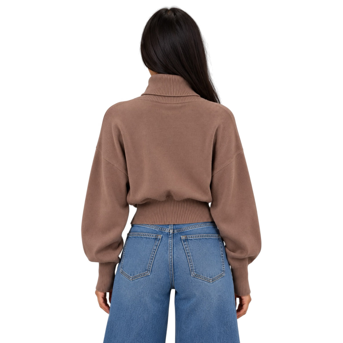 A woman viewed from the back wearing a cropped brown knit sweater with a high ribbed turtleneck and blue jeans, against a plain white background.