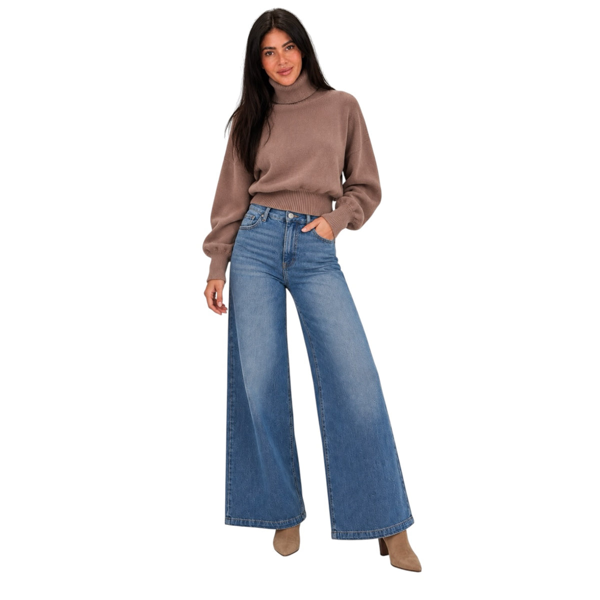 A woman modeling a brown ribbed turtleneck sweater and high-waisted, wide-leg blue jeans against a plain white background.