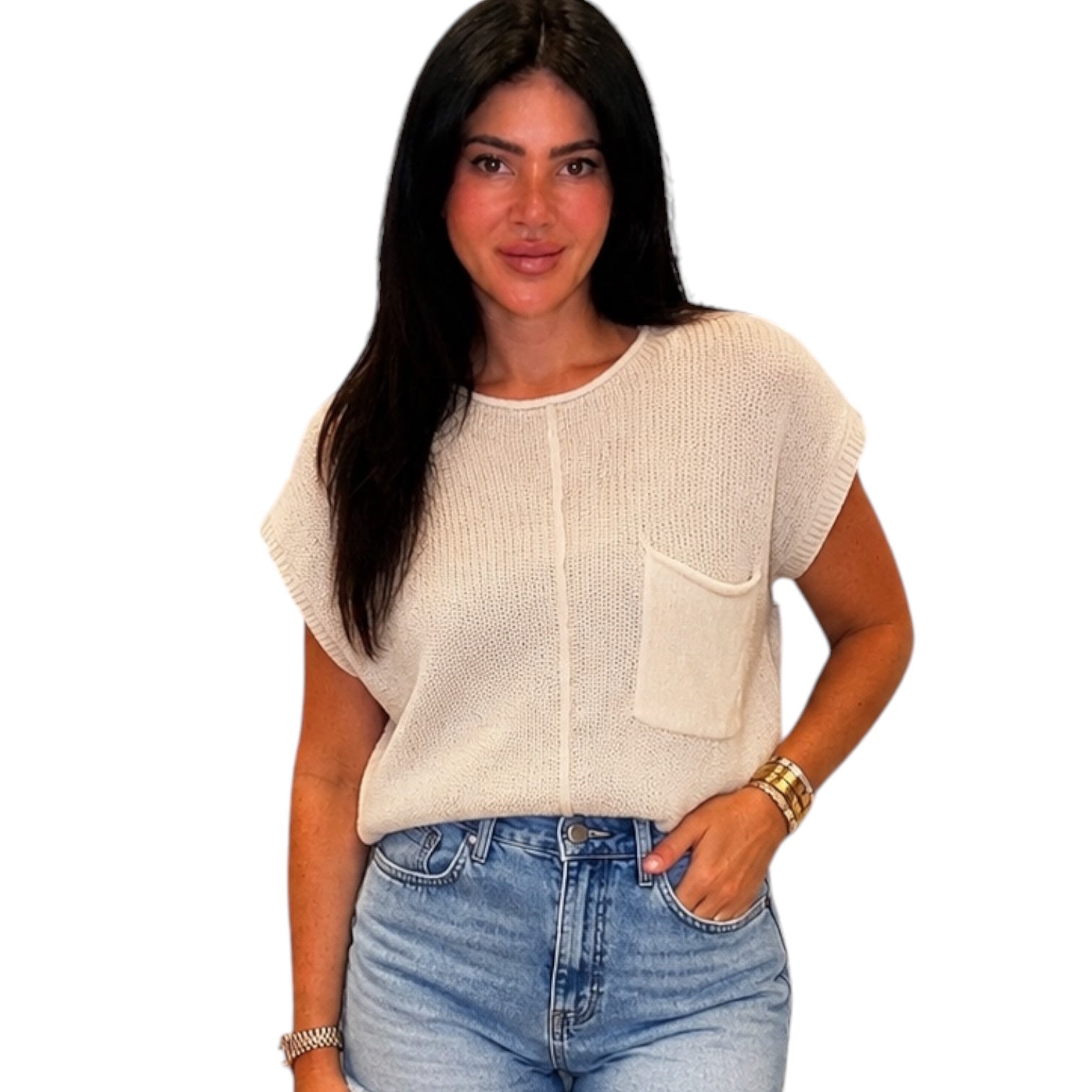 Woman wearing a beige knit top and blue jeans on a white background