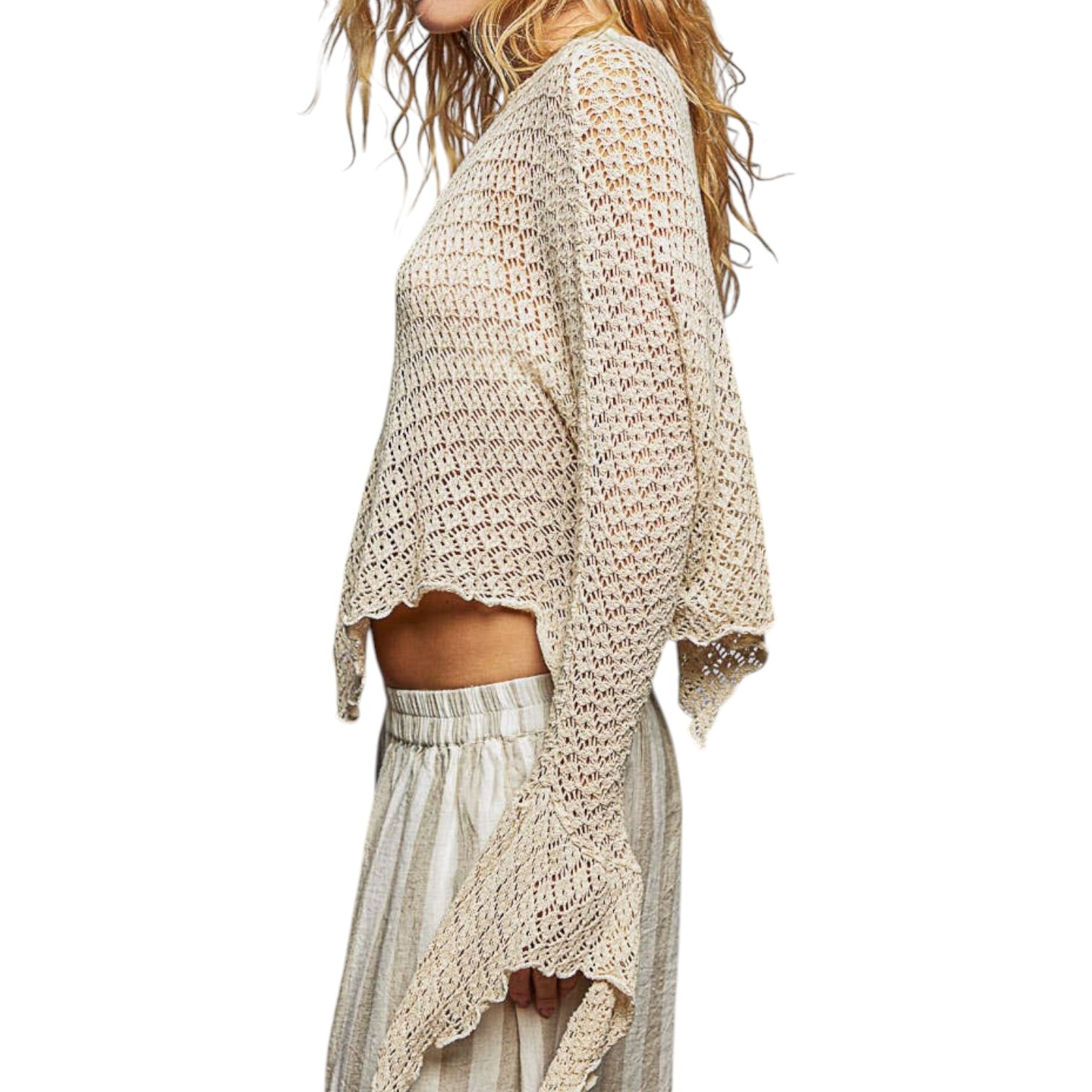 Woman wearing a beige crochet top and striped skirt on a white background