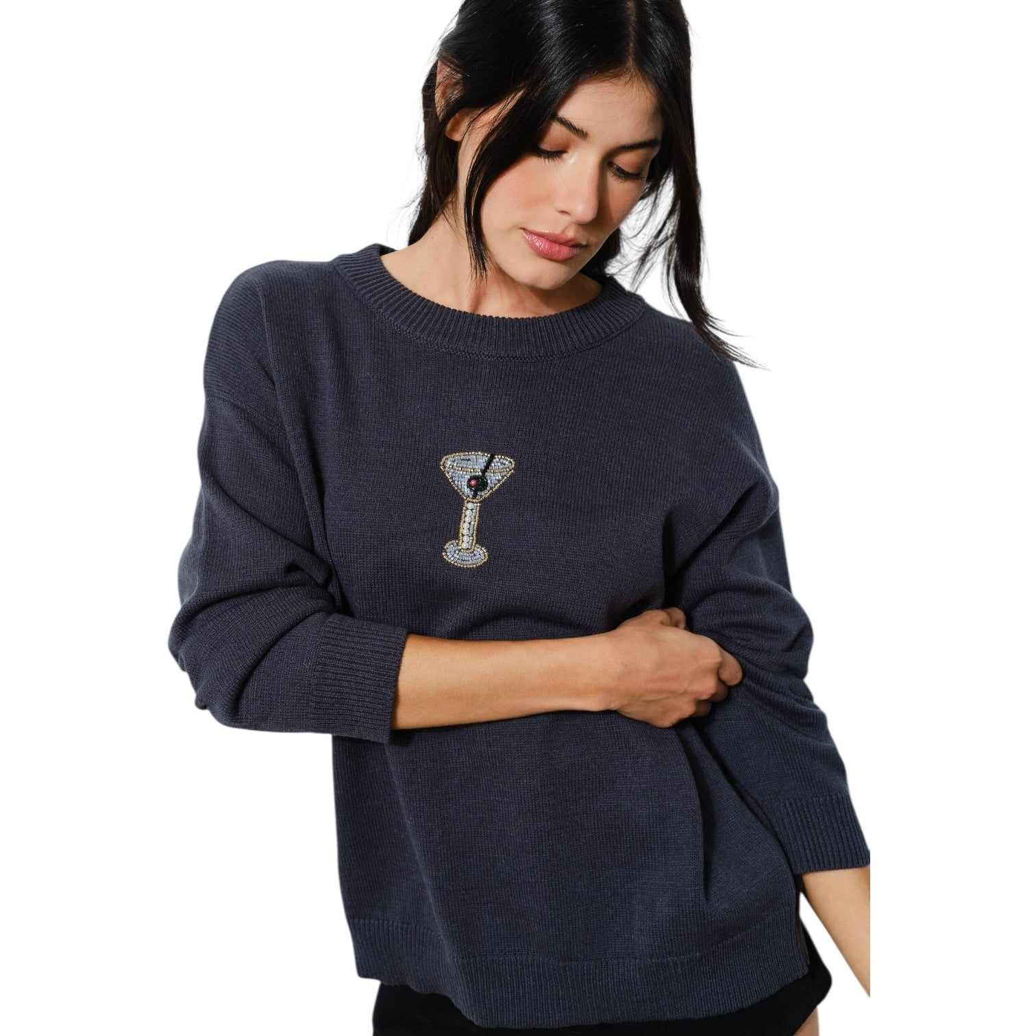 Woman wearing a navy blue sweater with a decorative martini on a white background
