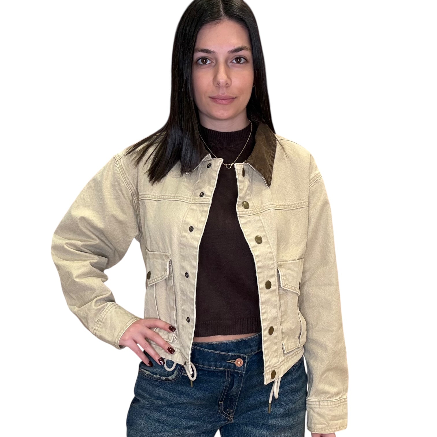 Woman wearing a beige denim jacket over a black top and blue jeans on a white background