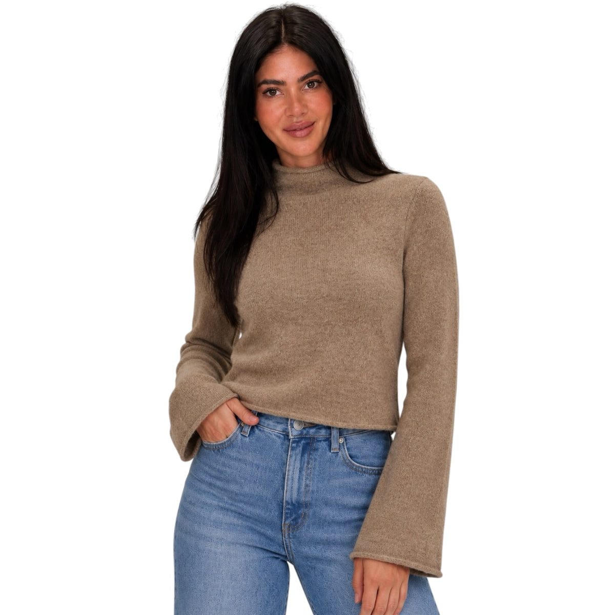 A woman modeling a cropped, long-sleeve knit sweater in a warm taupe-brown color, paired with blue jeans, against a plain white background.