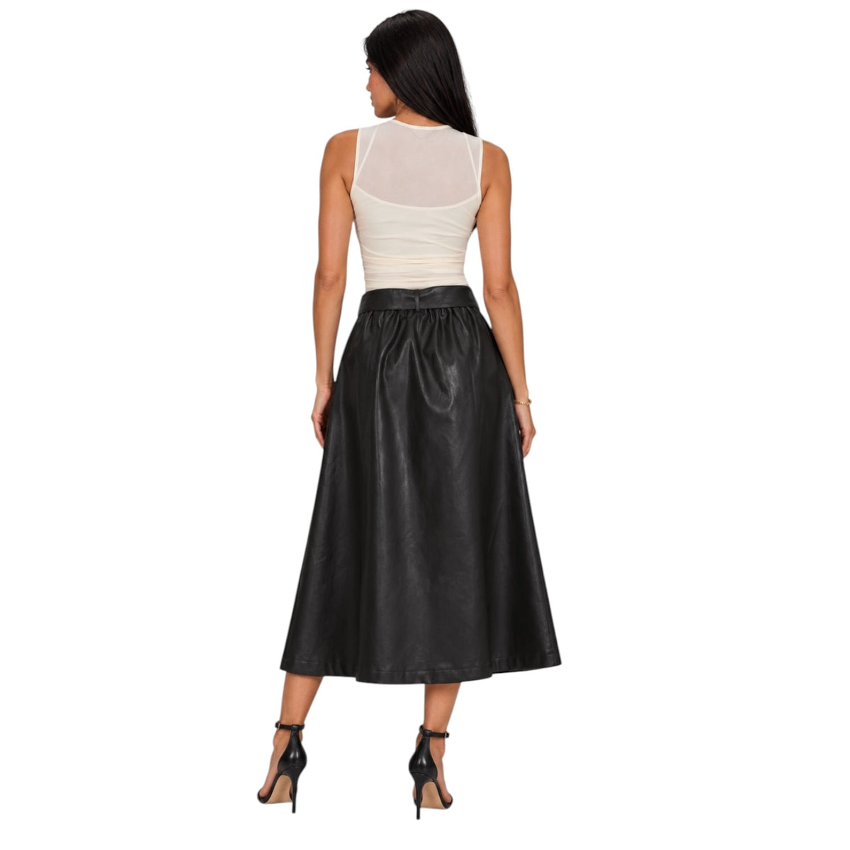 A woman shown from the back wearing a sleeveless white top with a sheer back panel and a high-waisted black faux-leather midi skirt, paired with black high-heeled sandals, against a plain white background.