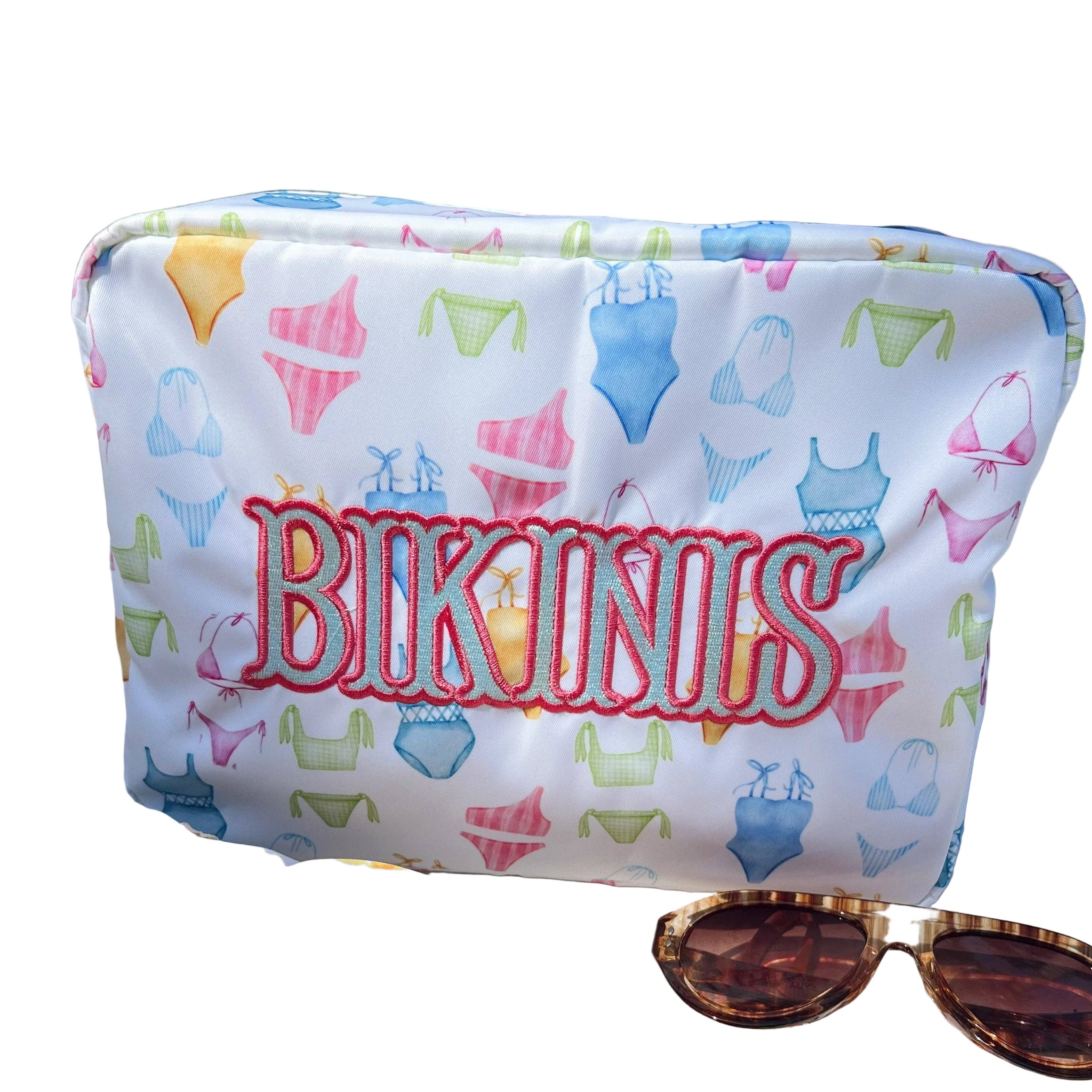 Colorful bikini set with a pouch labeled 'Bikinis' on a sunlit surface.