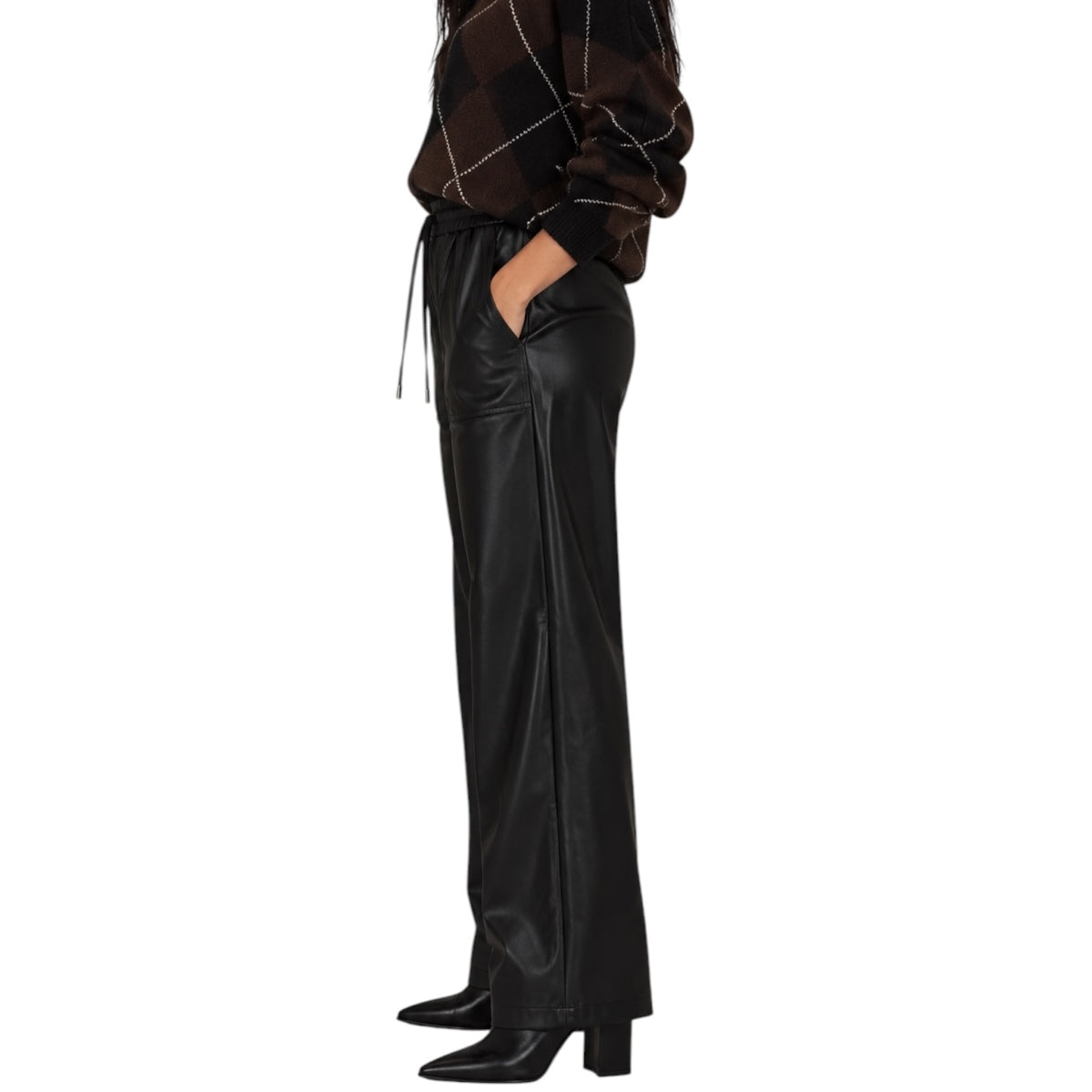 A model shown from the waist down wearing black wide-leg faux leather trousers with side slits, paired with a brown and black argyle sweater and black pointed-toe heels, against a plain white background.