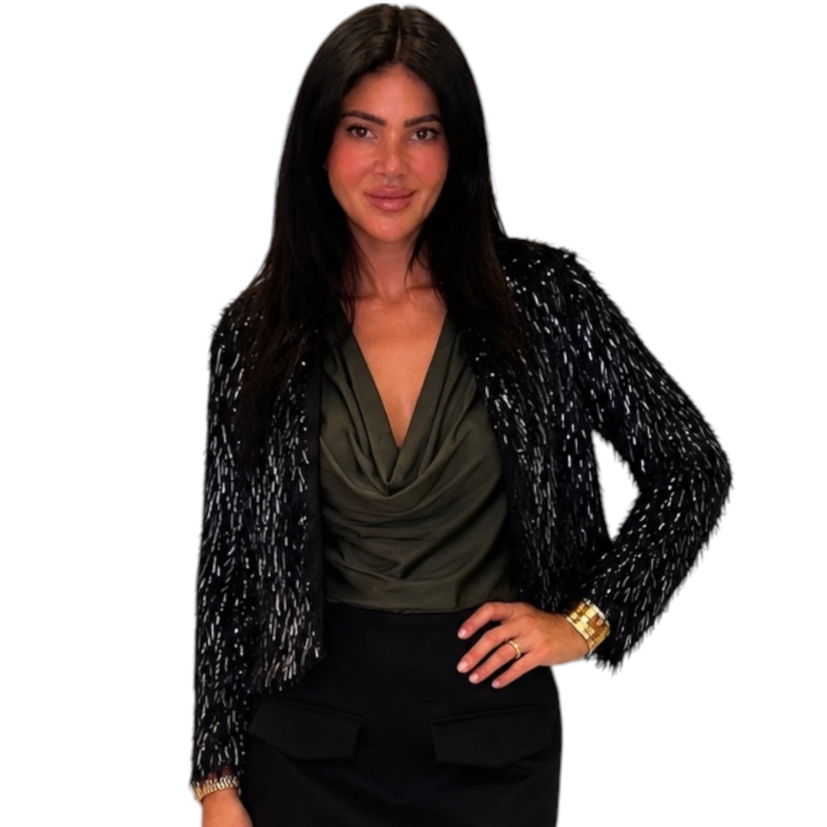 A woman modeling a black long-sleeve textured jacket with silver glitter-like flecks over an olive green cowl-neck top and black skirt, against a plain white background.