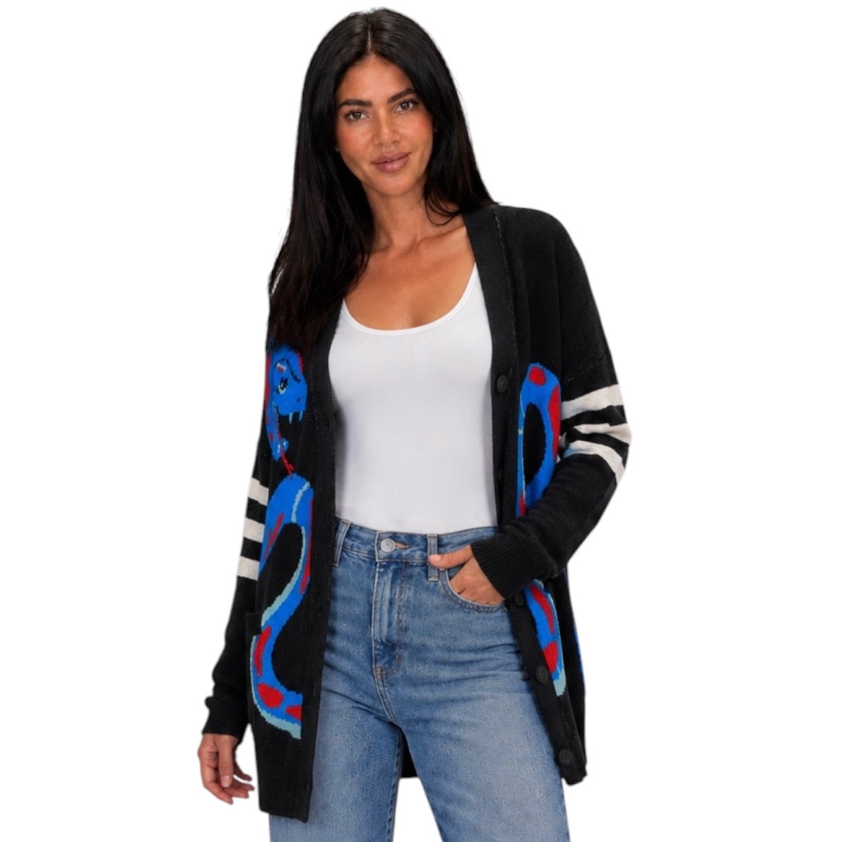 A woman modeling a black open-front cardigan with colorful snake graphics and striped sleeves, worn over a white tank top and blue jeans against a plain white background.