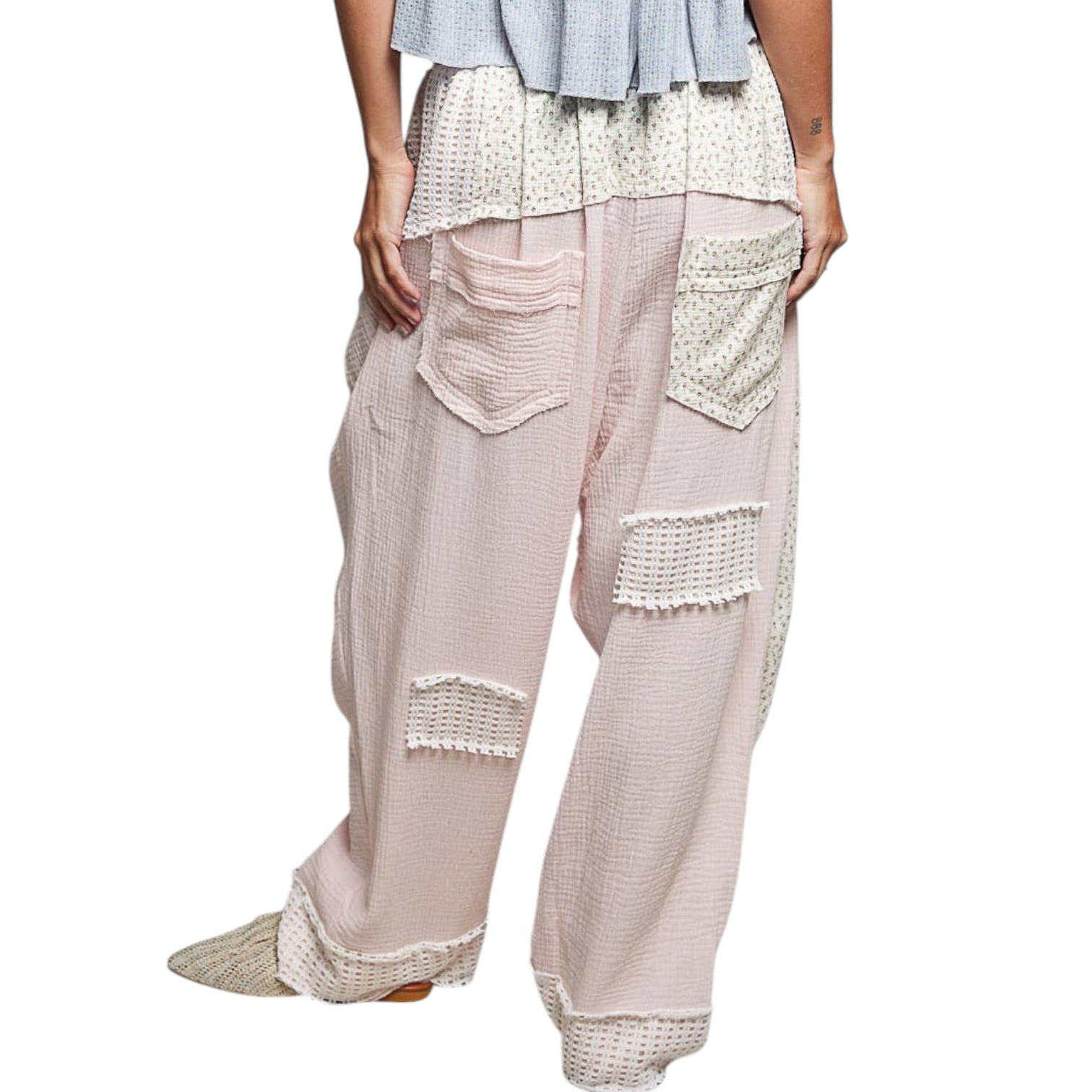 Light pink patchwork pants with decorative stitching on a white background
