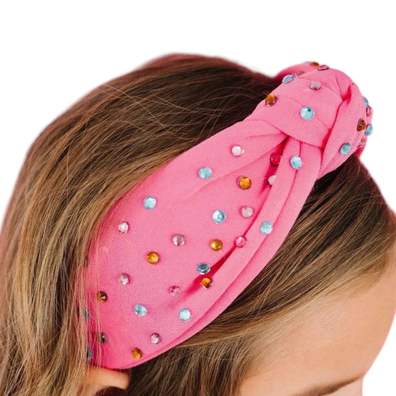 Pink headband with colorful embellishments on a person's head against a white background