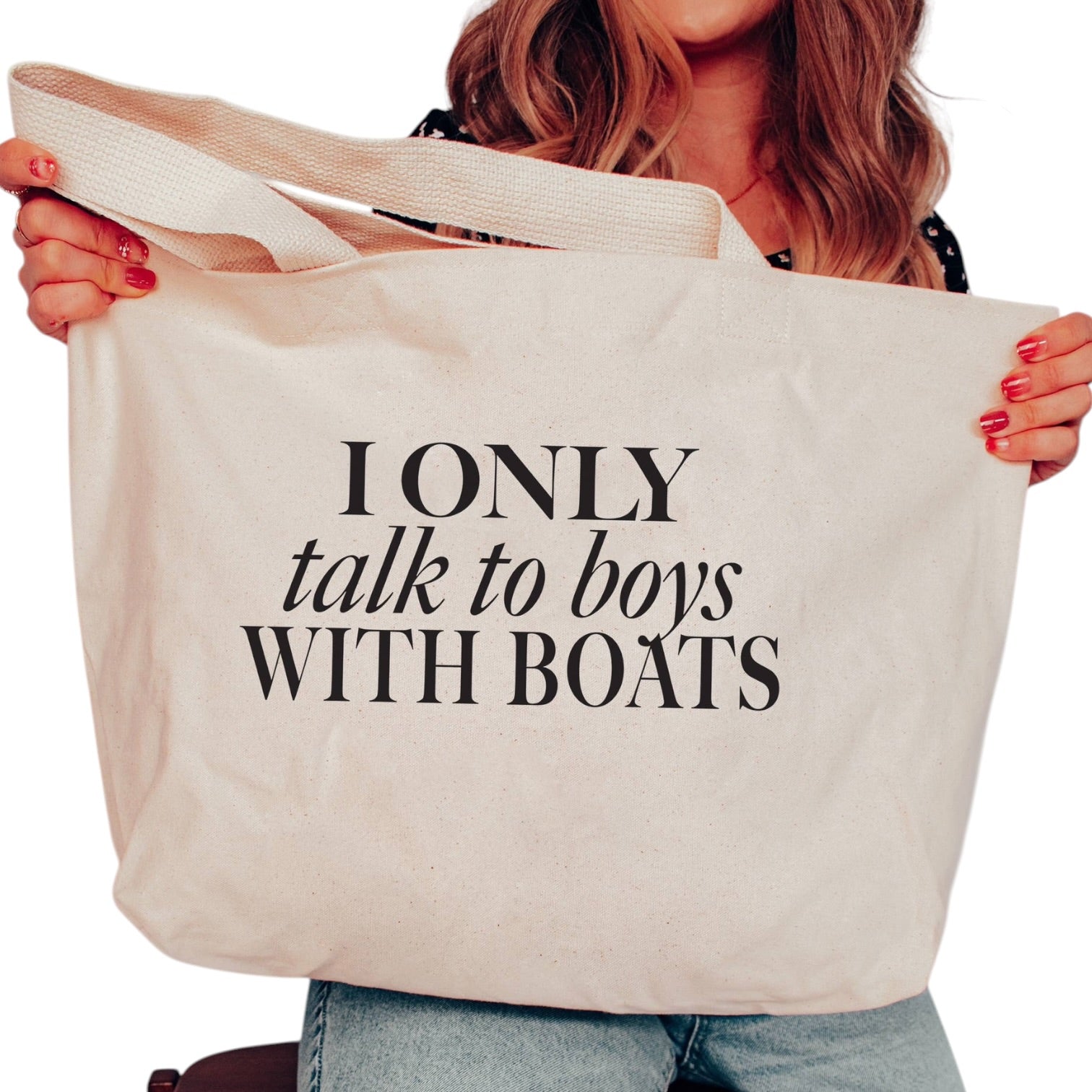 Person holding a tote bag with text 'I ONLY talk to boys WITH BOATS' on a white background