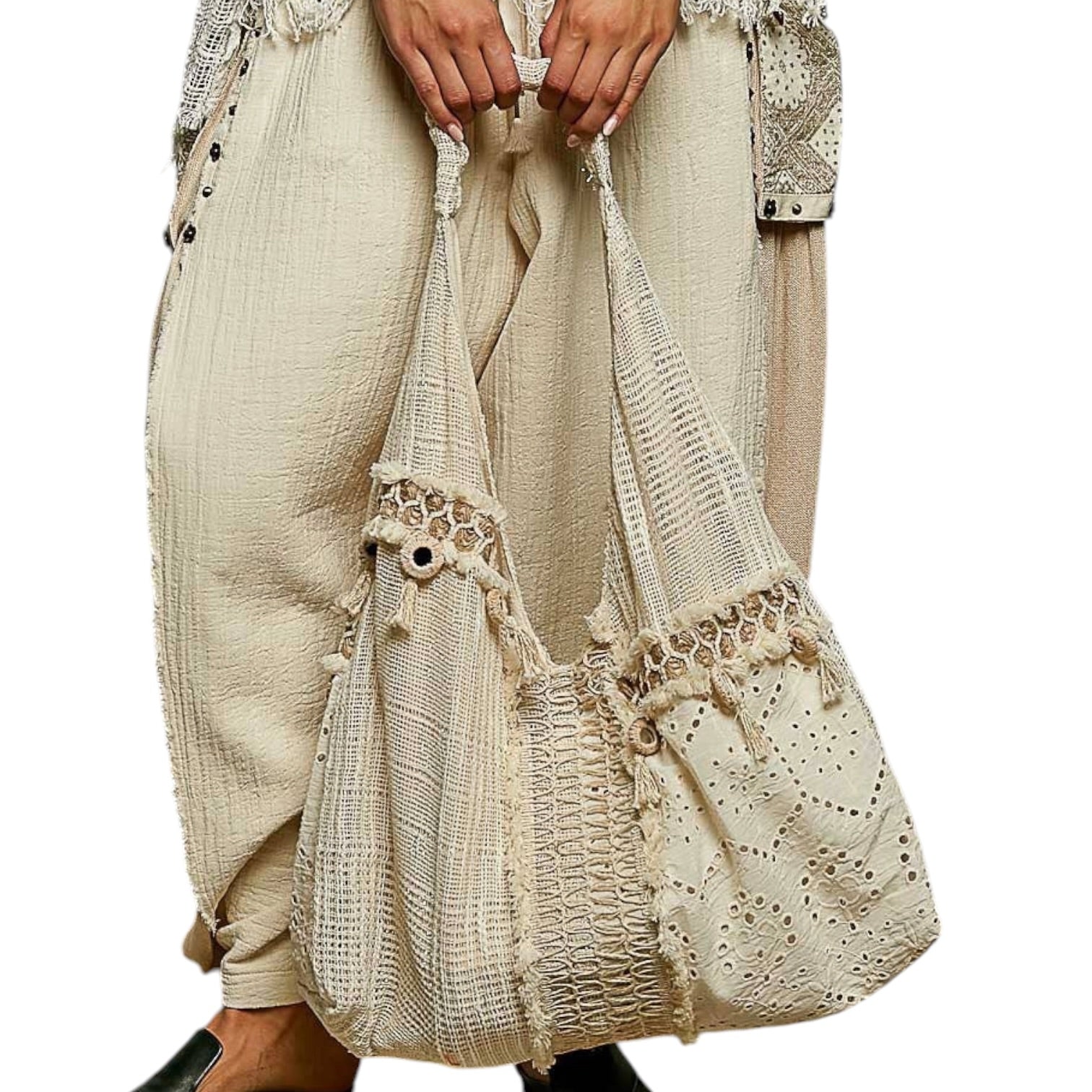 Beige textured bag with lace details held by a person wearing a matching outfit.