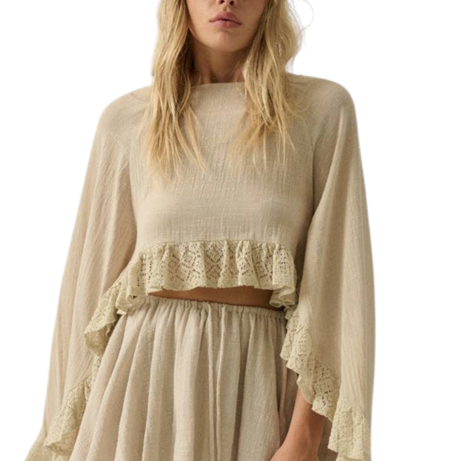 Woman wearing a beige long-sleeve top and skirt with lace details on a white background