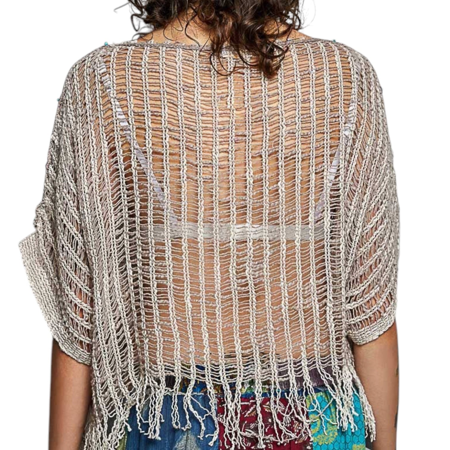 Back view of a person wearing a beige crochet shrug with tassels on a white background