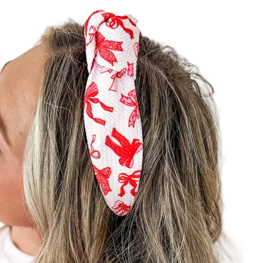 Person wearing a red headband with white floral pattern on a plain background