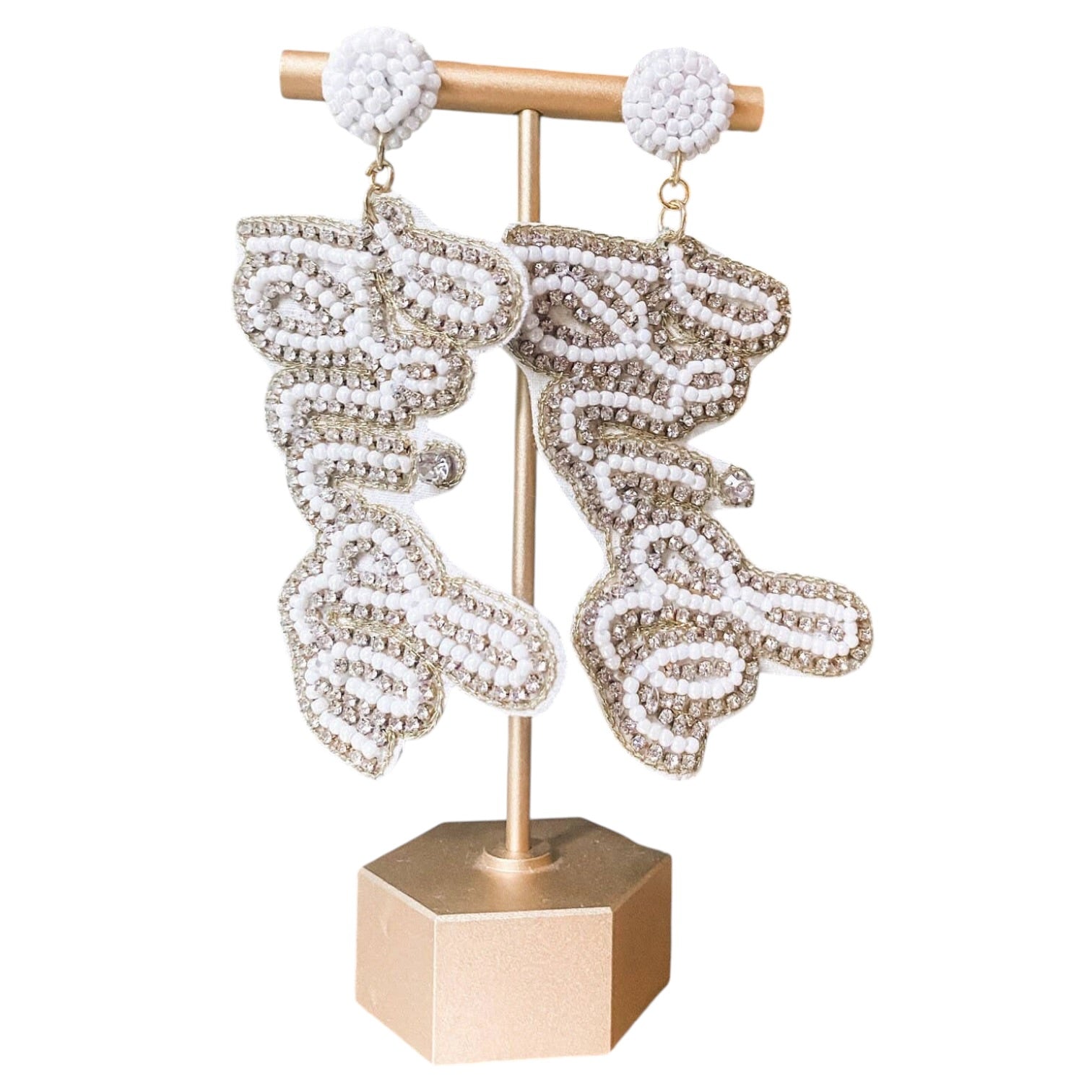 Pair of bride-shaped earrings on a gold stand with a white background