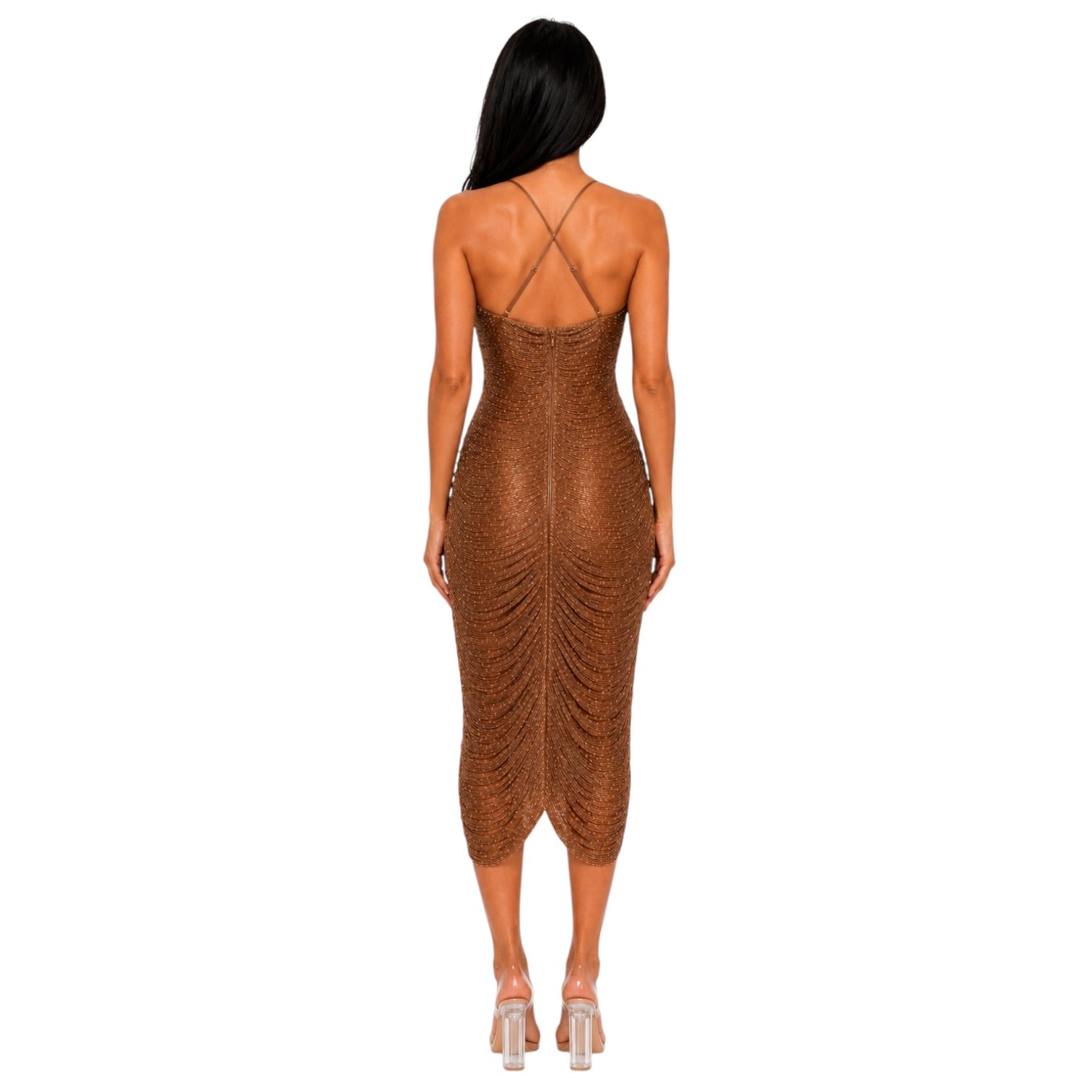 A woman viewed from the back wearing a fitted, ruched midi dress with thin crisscross straps and a textured metallic finish in a warm bronze-brown tone, paired with clear high-heel sandals on a plain white background.