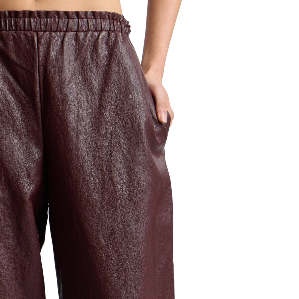 Close-up of a person wearing dark brown textured wide-leg pants with an elastic waistband and side pocket, shown against a plain white background.