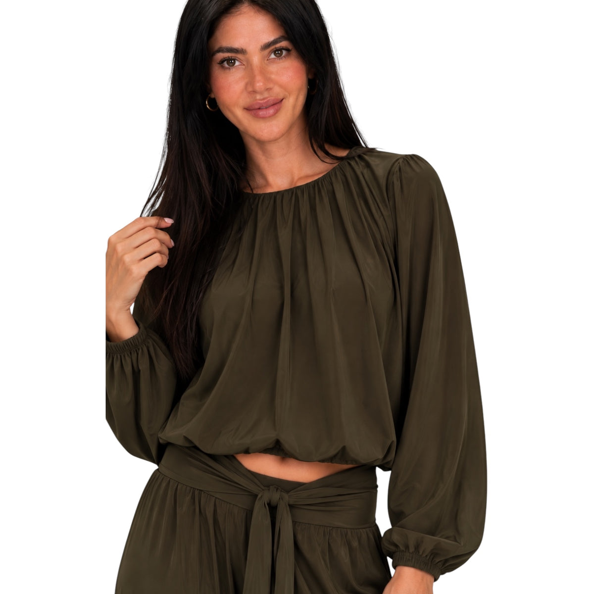 A woman wearing an olive green long-sleeve crop top with a gathered neckline and matching high-waisted tie-waist bottoms, shown against a plain white background.