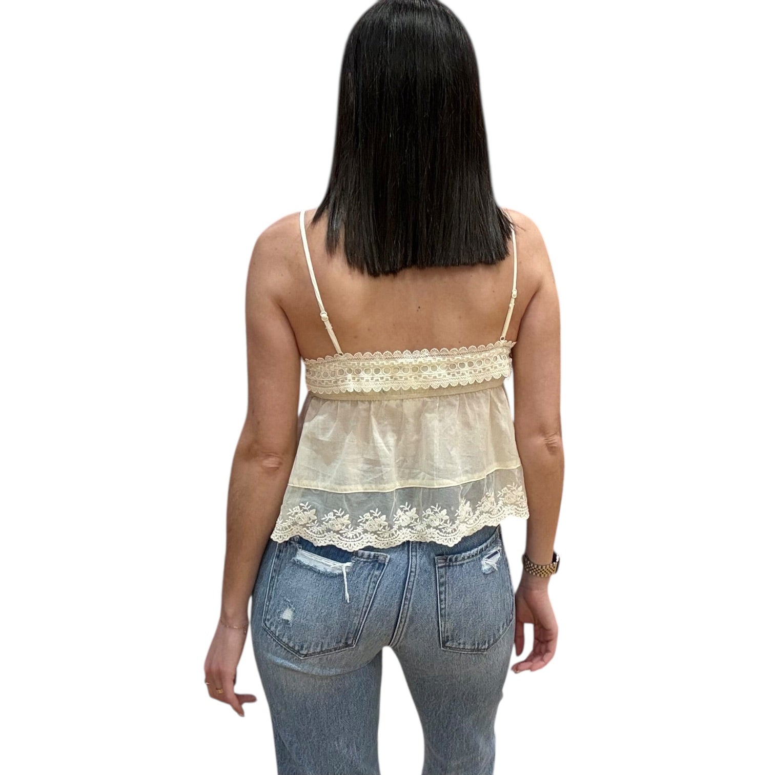 Woman wearing a beige lace top and blue jeans on a white background