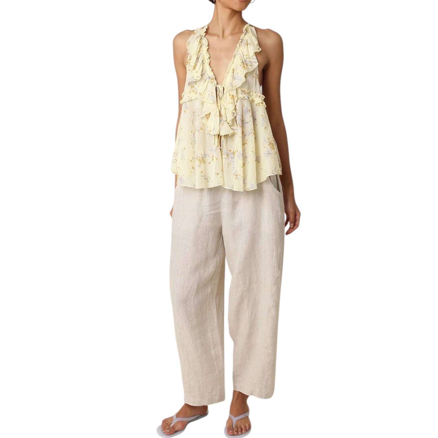 Woman wearing a yellow floral top and beige pants on a white background