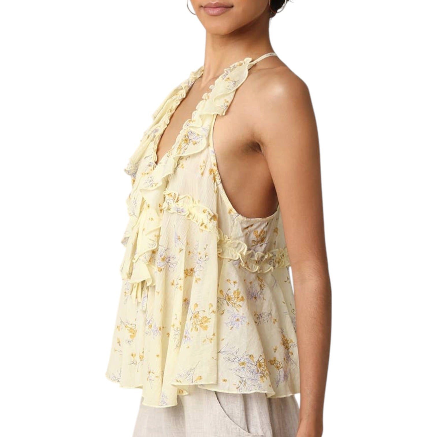 Woman wearing a light yellow floral sleeveless top on a white background