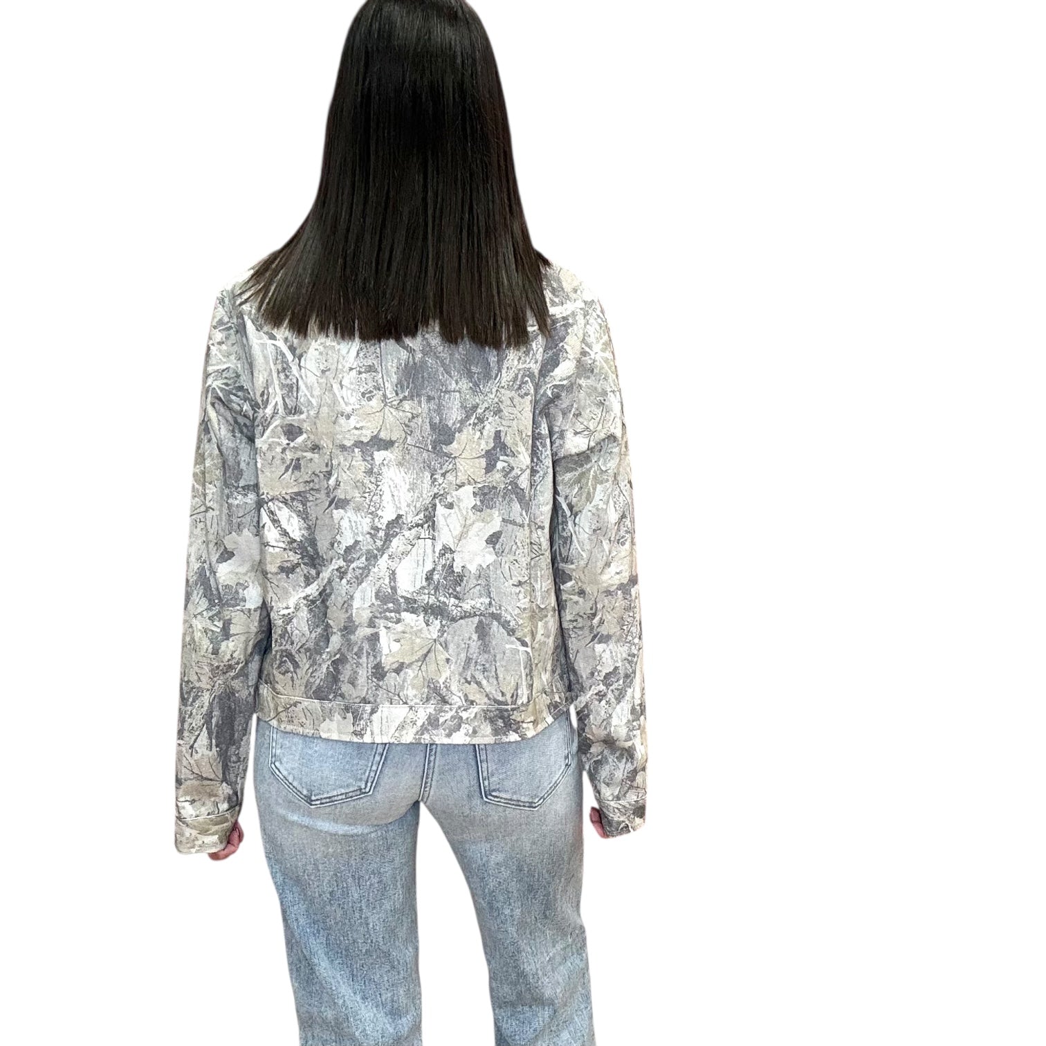 Person wearing a camo patterned jacket and jeans on a white background