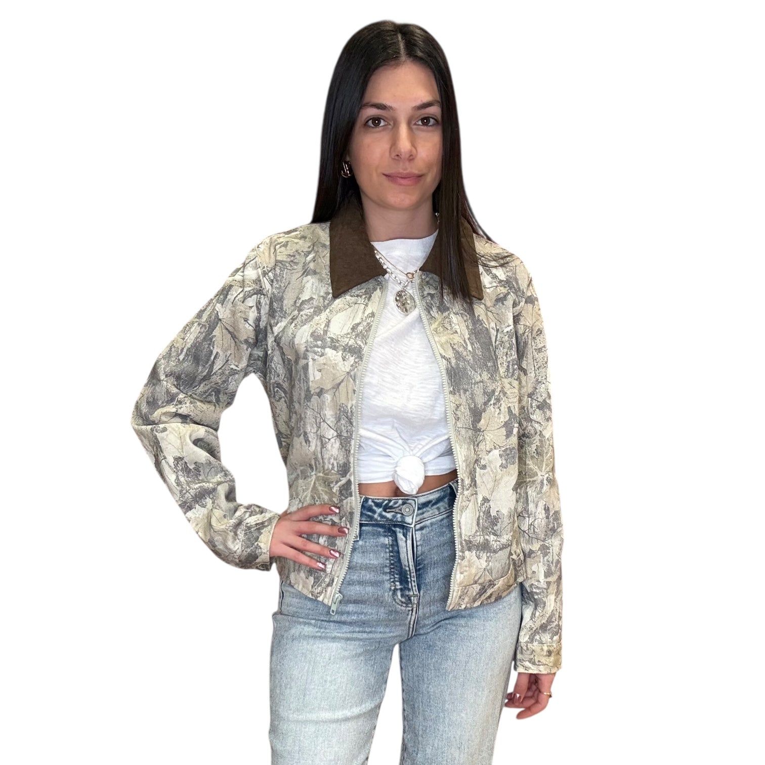 Woman wearing a camouflage jacket over a white shirt and blue jeans on a white background