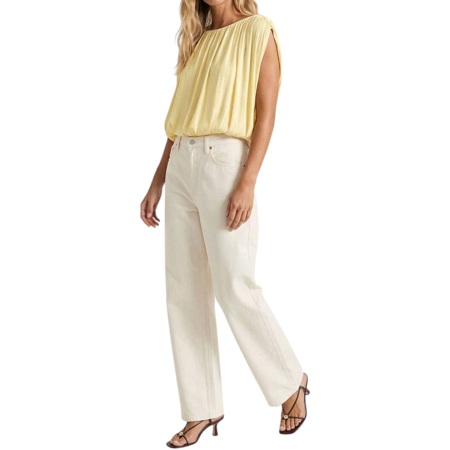 Woman wearing a yellow sleeveless top and white pants on a white background