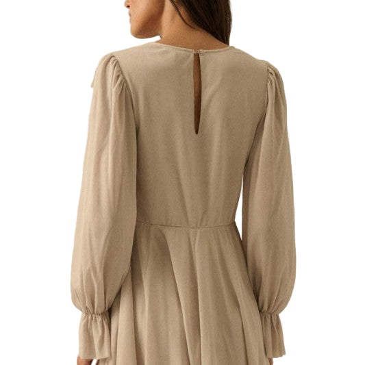 Woman wearing a beige romper with long sleeves on a white background