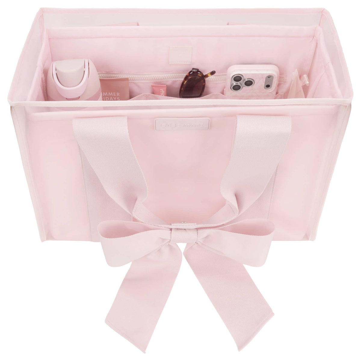 Pink fabric organizer with a bow, holding various items on a white background