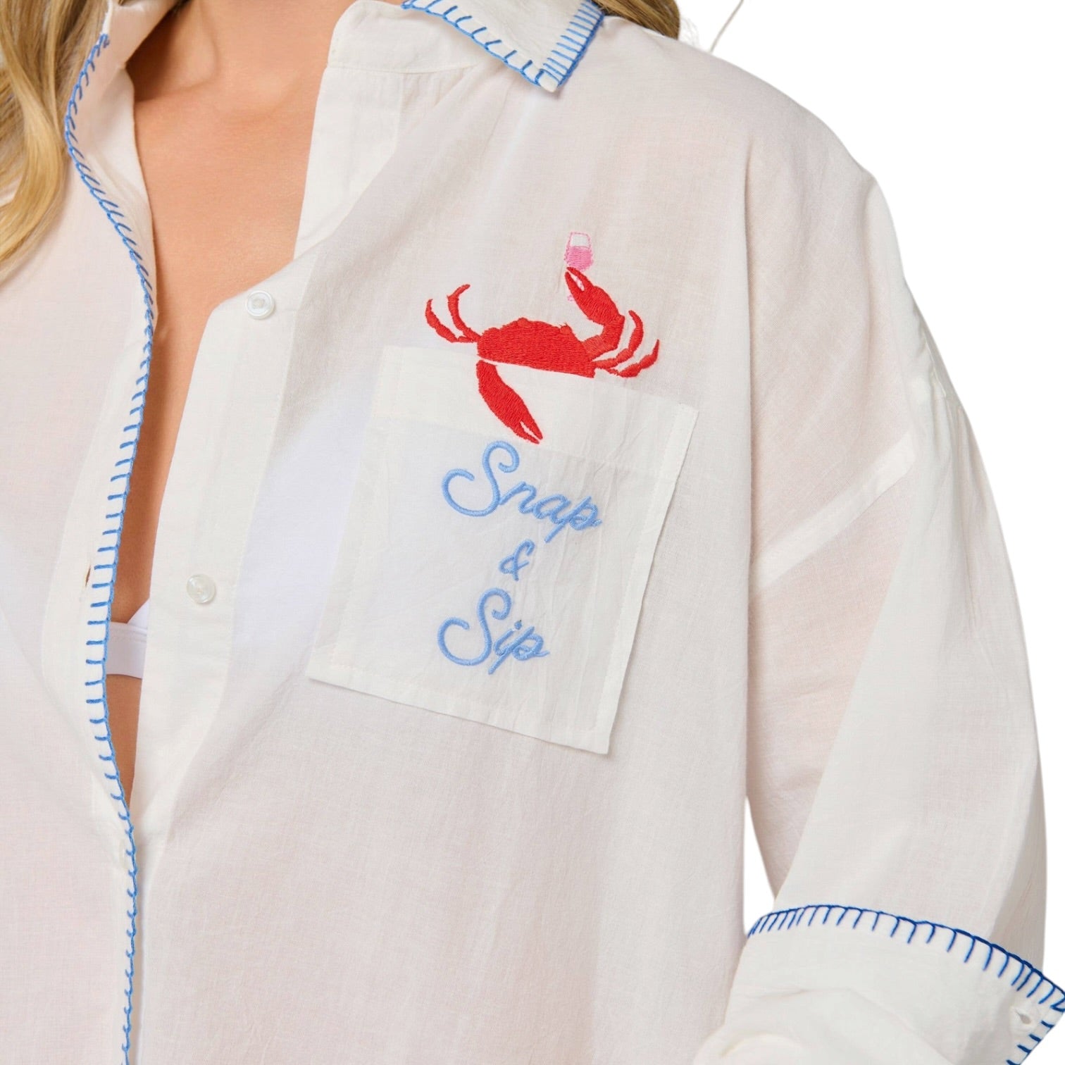 woman wearing white button down cover up with a crab with a wine glass coming out of the pocket that says "Snap & Sip" on white background.