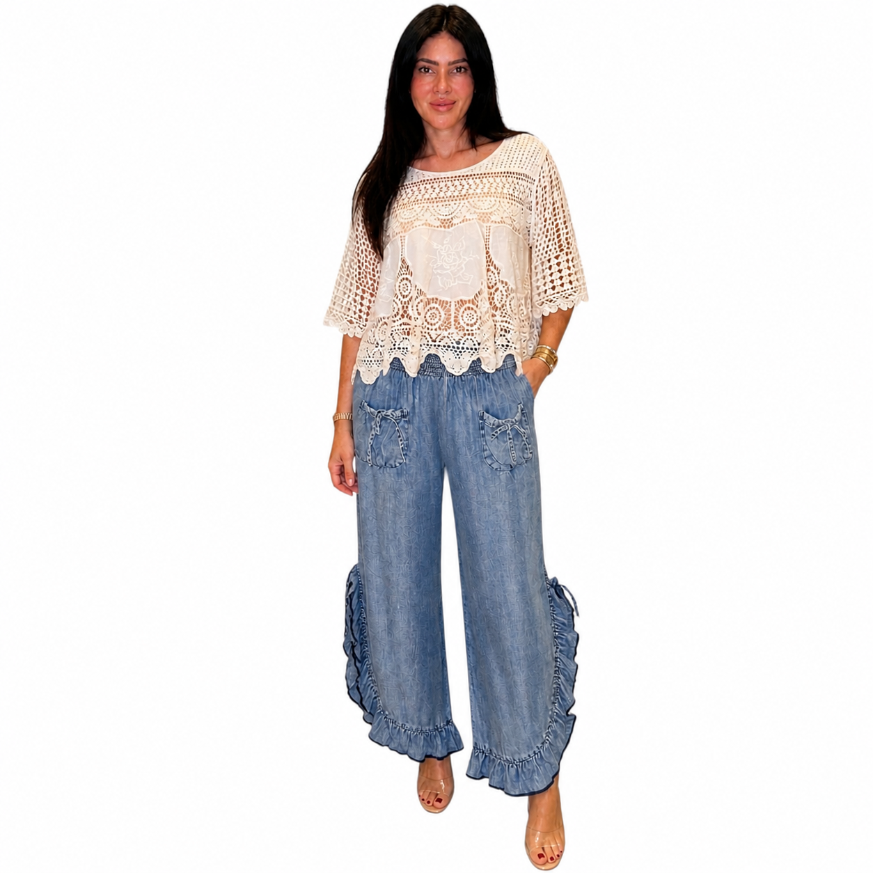 Person wearing a beige crochet top and chambray pants on a white background