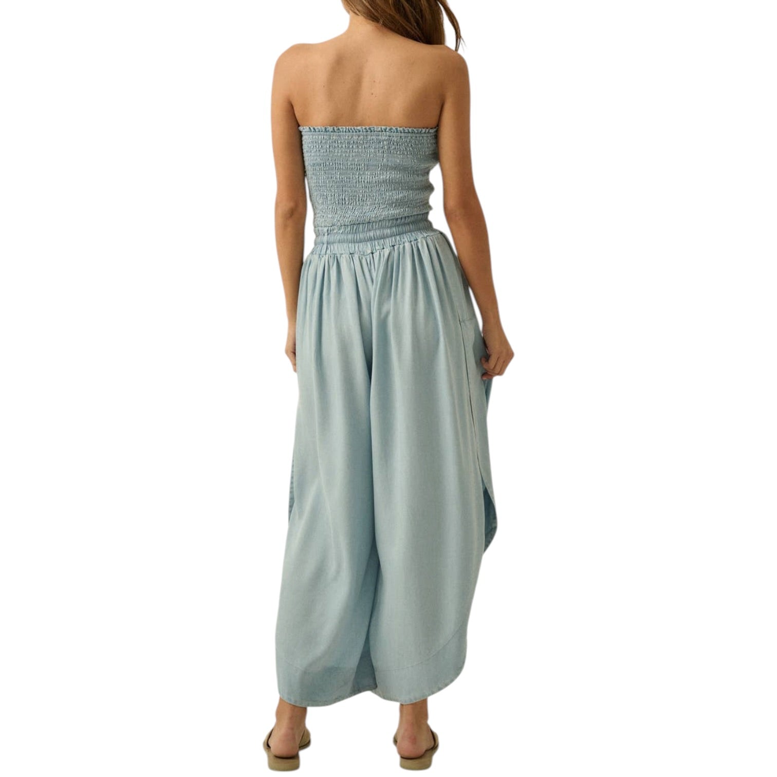 Woman wearing a strapless light blue jumpsuit on a white background