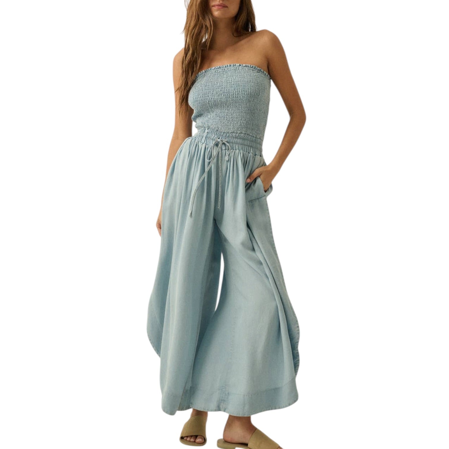 Woman wearing a light blue strapless jumpsuit on a white background