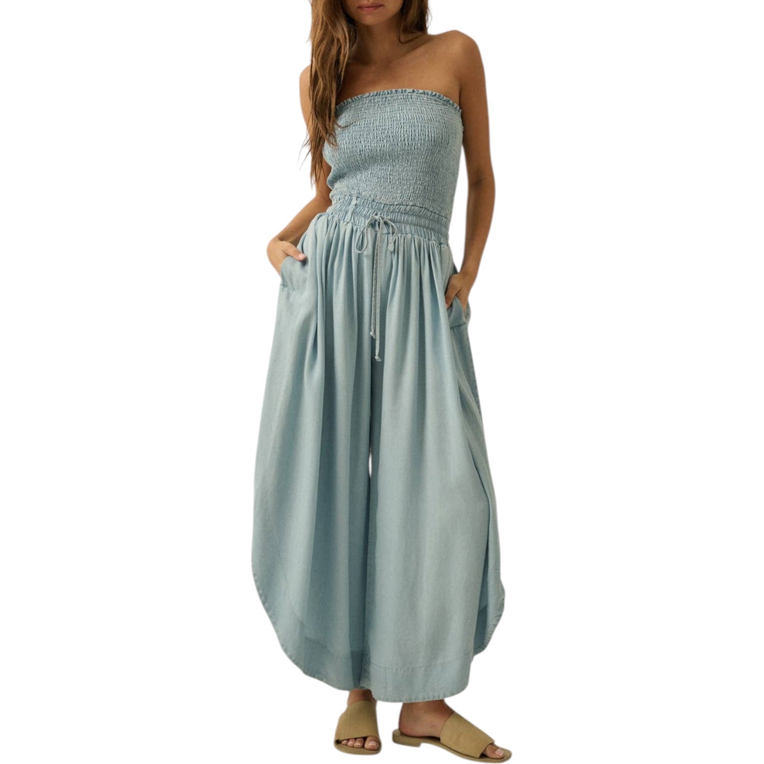 Woman wearing a strapless, light blue jumpsuit on a white background