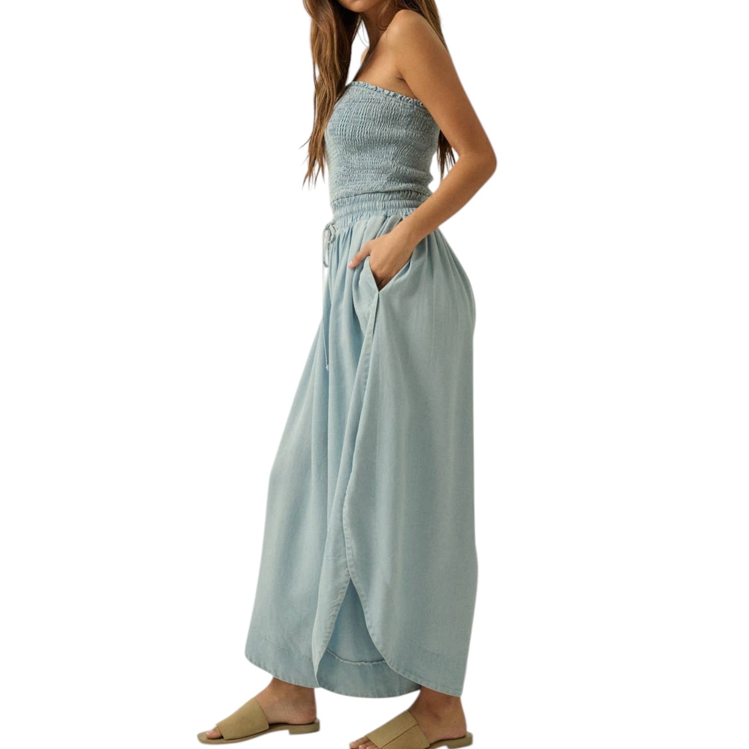 Woman wearing a light blue strapless jumpsuit with a patterned top on a white background